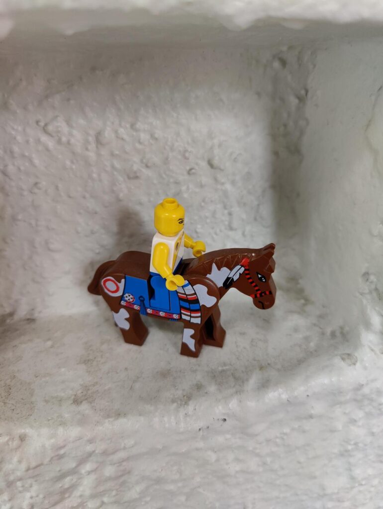 LEGO-Figur reitet auf einem braun-weiß gefleckten Pferd in einer Nische – Symbolbild für Co-Creation und kreative Zusammenarbeit in der Marktforschung.