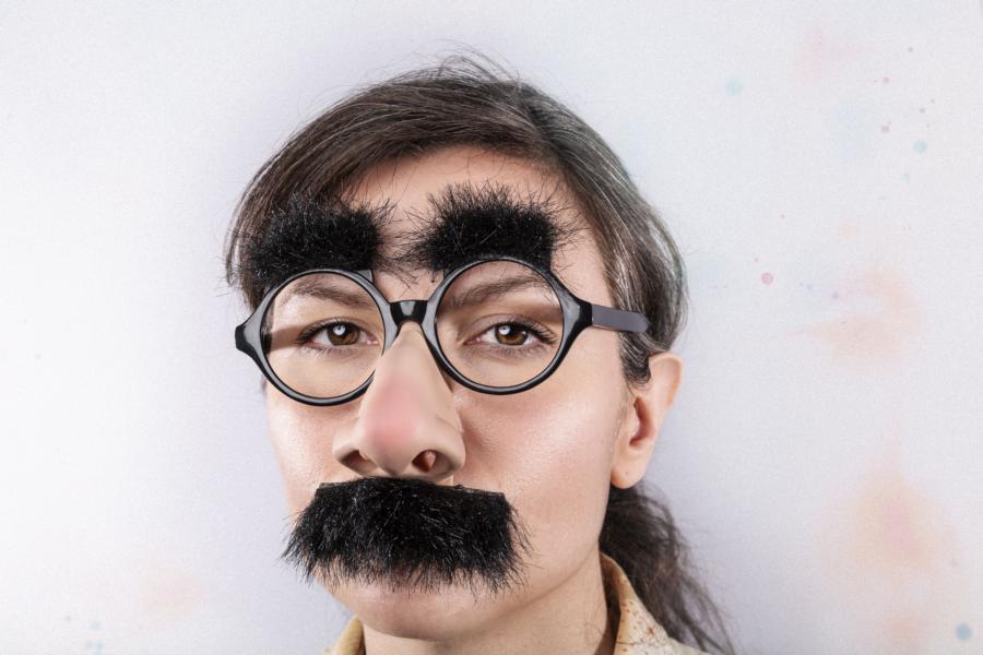 Porträt einer Person mit Spaßverkleidung (runder Brille, falschen buschigen Augenbrauen, Schnurrbart und Nase) – Symbolbild für Social Media Filter, Selbstdarstellung und TikTok-Trends.